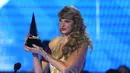 Taylor Swift menerima penghargaan untuk album pop favorit untuk "Red (Taylor's Version)" di American Music Awards di Microsoft Theater di Los Angeles pada Minggu, 20 November 2022. Taylor Swift tampil Ia mengenakan pakaian panjang berwarna gold dengan rambutnya yang panjang bergelombang. (AP Photo/Chris Pizzello)