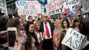 Sejumlah wanita seksi berbikini mengililingi seniman berpenampilan seperti Donald Trump saat unjuk rasa di depan Times Square, New York (25/10). Aksi ini dilakukan oleh seniman Alison Jackson. (AFP Photo/Drew Angerer/Getty Images)