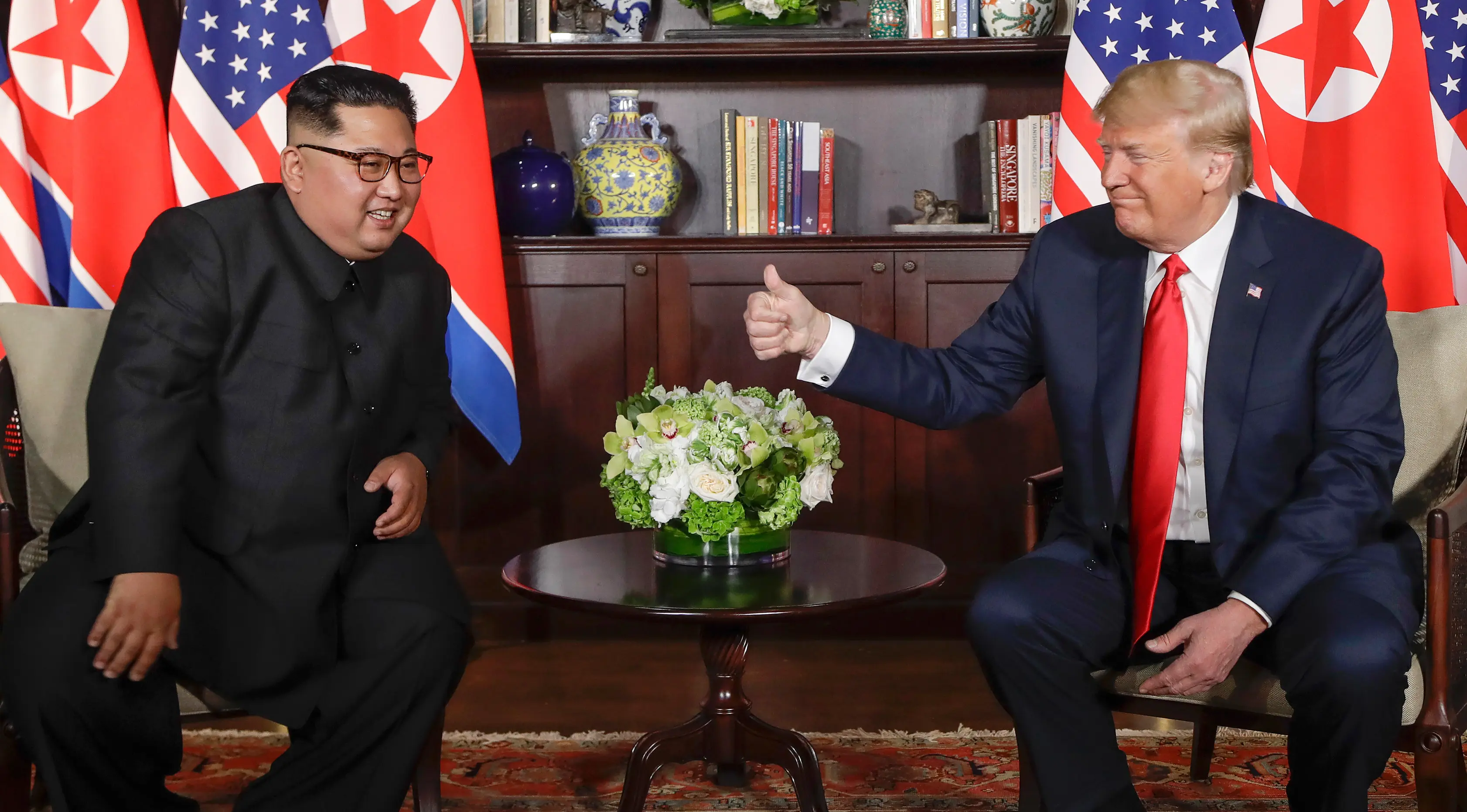 Presiden AS Donald Trump  memberikan jempolnya seusai berjabat tangan dengan Pemimpin Korea Utara, Kim Jong-un dalam pertemuan bersejarah di resor Capella, Pulau Sentosa, Selasa (12/6). Trump dan Kim saling melemparkan senyum. (AP/Evan Vucci)