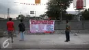 Sejumlah warga memperhatikan spanduk tolak penutupan jalan di perlintasan kereta Stasiun Senen, Jakarta, Senin (28/11). Warga menolak penutupan jalan di kawasan tersebut karena dianggap menimbulkan masalah baru. (Liputan6.com/Immanuel Antonius)