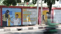 Pengendara melintasi mural bertema 'Tolak Kekerasan Perempuan dan Pelecehan Seksual' di kawasan Jatinegara, Jakarta, Senin (17/12). Mural tersebut juga mengajak masyarakat untuk melindungi kaum perempuan. (Merdeka.com/Iqbal S. Nugroho)