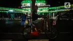 Pedagang melihat halte CSW yang berhiaskan lampu warna-warni di Kawasan Kebayoran Baru, Jakarta, Kamis (5/8/2021). Konsep desain Cakra Selaras Wahana tersebut memiliki arti sebagai lingkaran penghubung yang setara antar moda. (Liputan6.com/Johan Tallo)