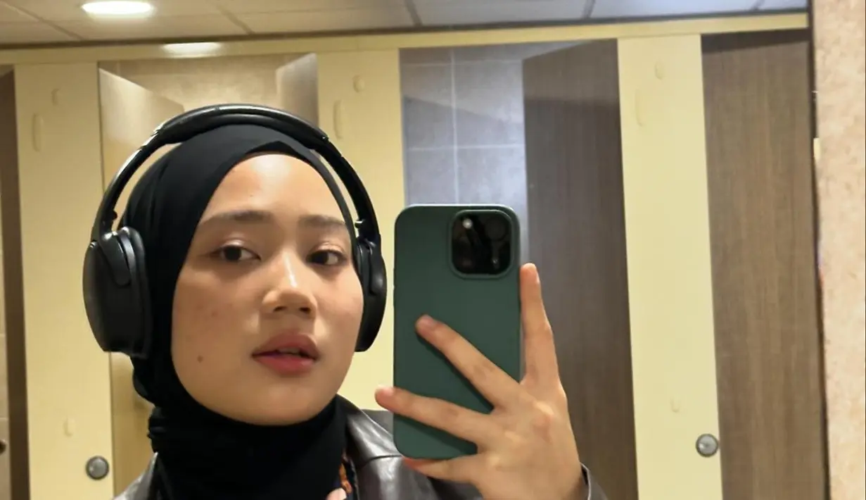 Zara melakukan mirror selfie. Dia mengenakan blouse yang dipadukan dengan jaket kulit dan jilbab hitam. Tampilannya begitu modis. (Foto: Instagram/ camilliazr)
