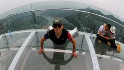 Seorang pria berpose saat mengunjungi platform kaca di Shilin Gorge, Beijing, Cina, (27/5). Objek wisata baru di China ini berada di ketinggian 768 meter dan berjarak 400 meter dari dasar jurang. (REUTERS/Kim Kyung-Hoon)
