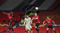 Gelandang Manchester United, Paul Pogba (kiri) menanduk bola yang berakhir sebagai gol kelima Manchester United ke gawang AS Roma dalam leg pertama semifinal Liga Europa di Old Trafford, Jumat (30/4/2021). Manchester United menang telak 6-2 atas AS Roma dalam laga ini. (Paul ELLIS / AFP)