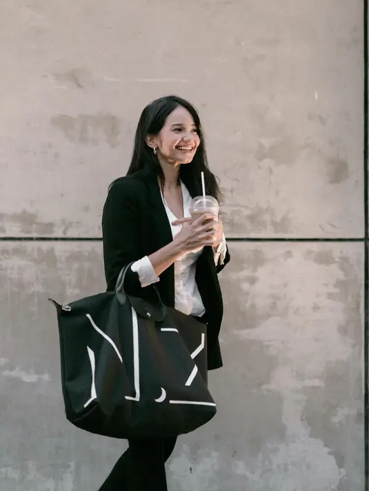 Enzy Storia mengenakan setelan workwear hitam-putih yang simple, namun tetap menawan. Dengan kemeja putih yang ia jadikan innerwear, ditumpuknya dengan blazer hitam, dan dipadu dengan celana panjang hitam, padu padan yang tak pernah salah. Ia juga tampak mengenakan alas kaki berwarna putih dan menenteng tas yang juga berwarna hitam-putih. Foto: Instagram.