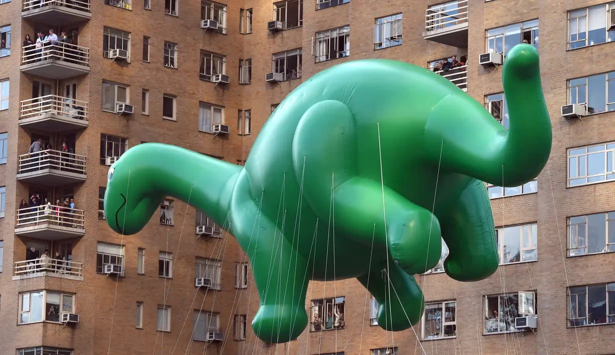 Balon raksaksa berbentuk Dino Saurus ikut meramaikan Parade Thanksgiving Day di New York City (26/11/2015). Beragam balon raksaksa yang dibuat seperti tokoh animasi menjadi suguhan utama dalam perayaan tersebut. (AFP Photo/Timothy A. Clary)