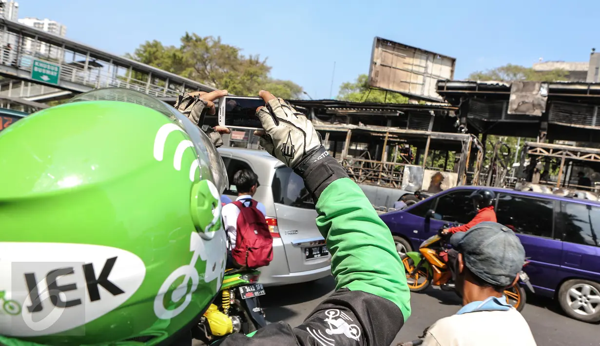 Warga mengabadikan gambar bangkai Bus Transjakarta yang terbakar di Halte UI Salemba, Jakarta, Jumat (3/7). Bus Koridor V jurusan Ancol-Kampung Melayu tersebut terbakar sekitar pukul 08.30 WIB. (Liputan6.com/Faizal Fanani)