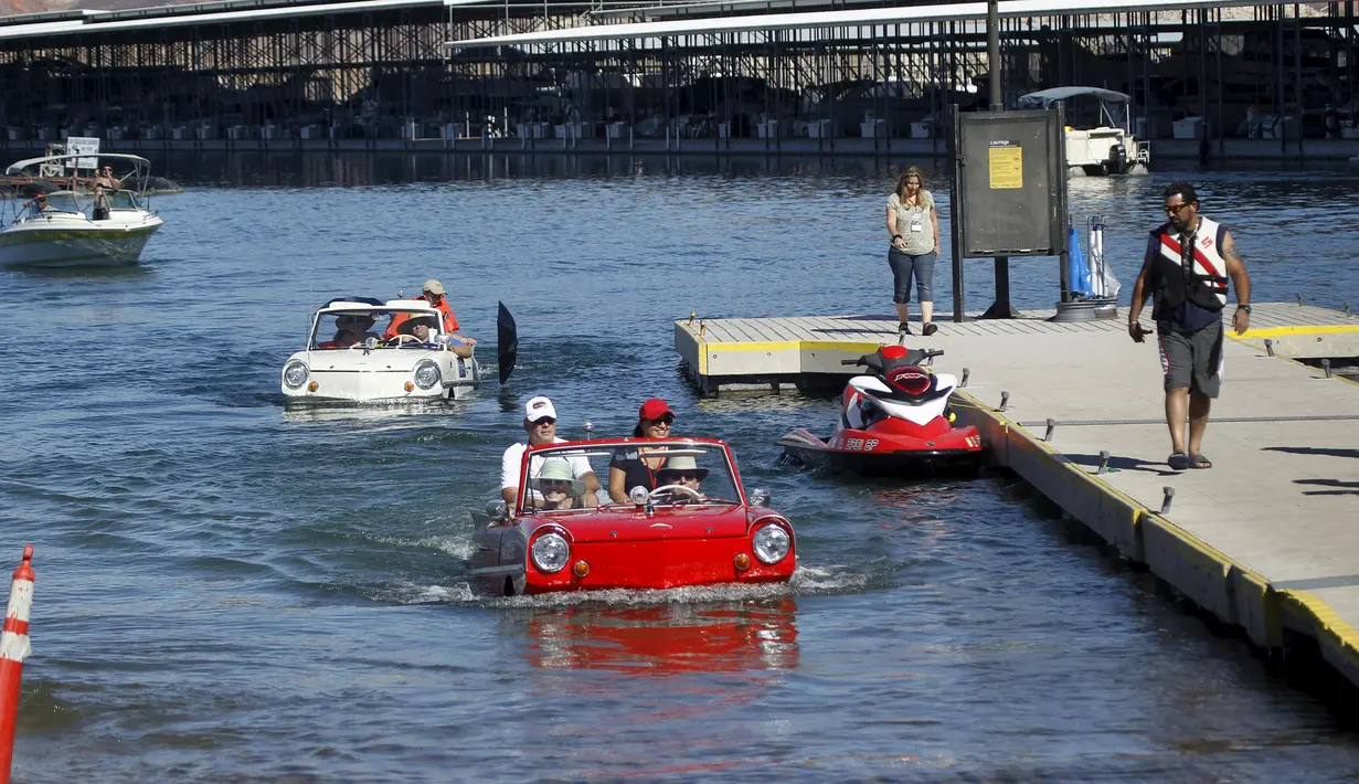 Sebuah 1965 Amphicar (kiri) dikemudikan Dean Baker dan Amphicar 1963 dikemudikan oleh Rob Vondracek saat festival Las Vegas Amphicar Swim di Danau Mead, Nevada, Jumat (9/10). (REUTERS/Steve Marcus)