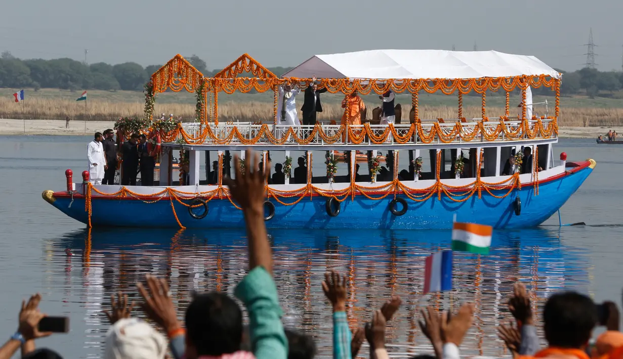 Presiden Prancis Emmanuel Macron bersama PM India Narendra Modi melambaikan tangan saat mereka naik perahu di Sungai Gangga di Varanasi, India, Senin (12/3). Perahu yang membawa keduanya berhias bunga marigold. (AP Photo/Rajesh Kumar Singh)