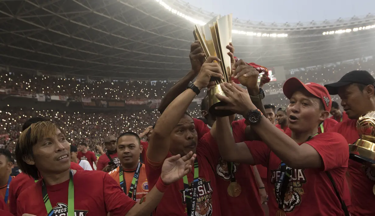 Tim oficial Persija Jakarta mengangkat piala usai mengalahkan Mitra Kukar pada laga Liga 1 di SUGBK, Jakarta, Minggu (9/12). Persija menang 2-1 atas Mitra. (Bola.com/Vitalis Yogi Trisna)