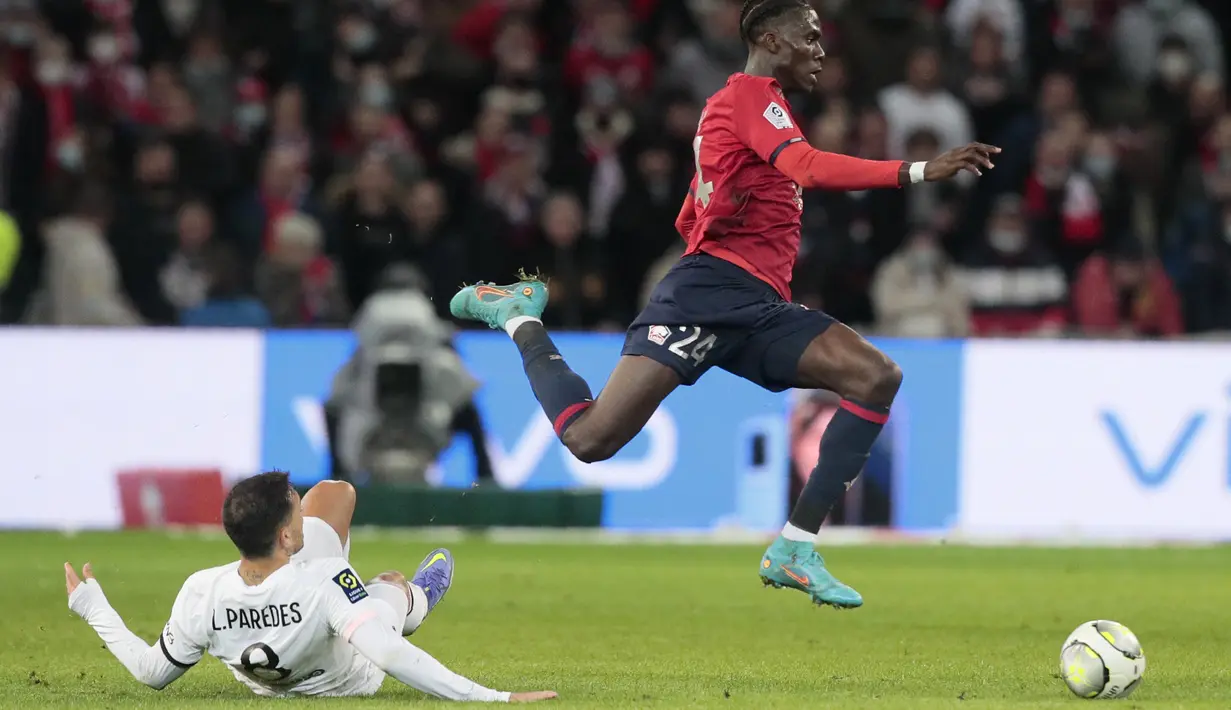 Gelandang Lille Amadou Onana ditekel oleh gelandang Paris Saint-Germain (PSG) Leandro Paredes dalam lanjutan Liga Prancis di Stadion Pierre-Mauroy, Senin (7/2/2022) dinihari WIB. PSG mengalahkan juara bertahan Lille dengan skor 5-1. (AP Photo/Michel Spingler)