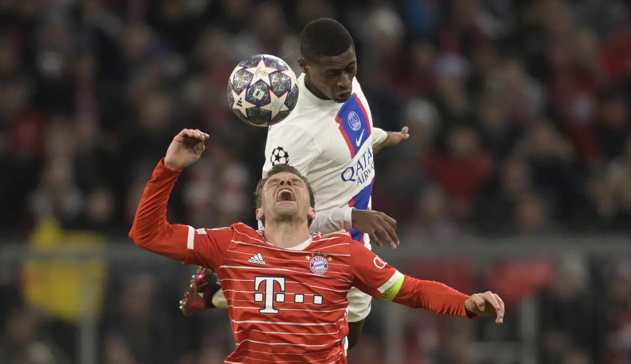 Penyerang Bayern Munchen, Thomas Mueller melompat berebut bola dengan pemain PSG, Nuno Mendes pada pertandingan leg 2 babak 16 besar Liga Champions di Allianz Arena di Munich, Jerman, Kamis (9/3/2023). Bayern menang atas PSG dengan 2-0. (AP Photo/Matthias Schrader)