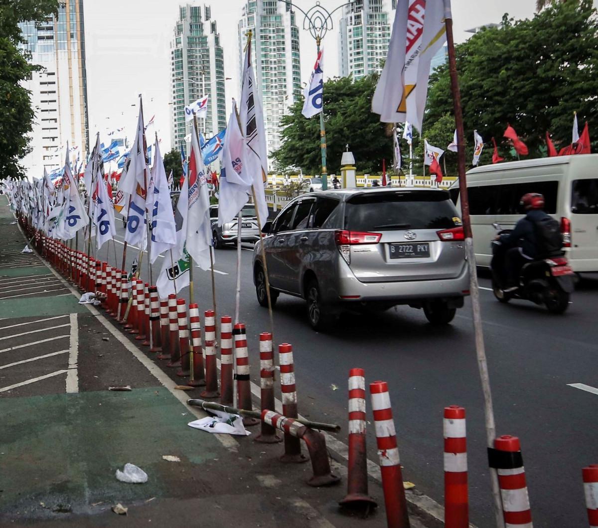 Ratusan alat peraga kampanye (APK) bendera partai politik terpasang di pembatas plastik jalur sepeda (stick cone) di kawasan Jalan Rasuna Said, Jakarta Selatan, Senin  (8/1/2024).