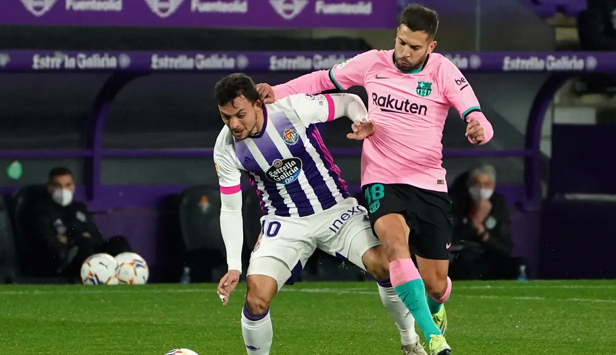 Bek Barcelona, Jordi Alba, berebut bola dengan gelandang Valladolid, Oscar Plano, pada laga lanjutan Liga Spanyol di Jose Zorrilla Stadium, Rabu (23/12/2020) dini hari WIB. Barcelona menang 3-0 atas Valladolid. (AFP/Cesar Manso)