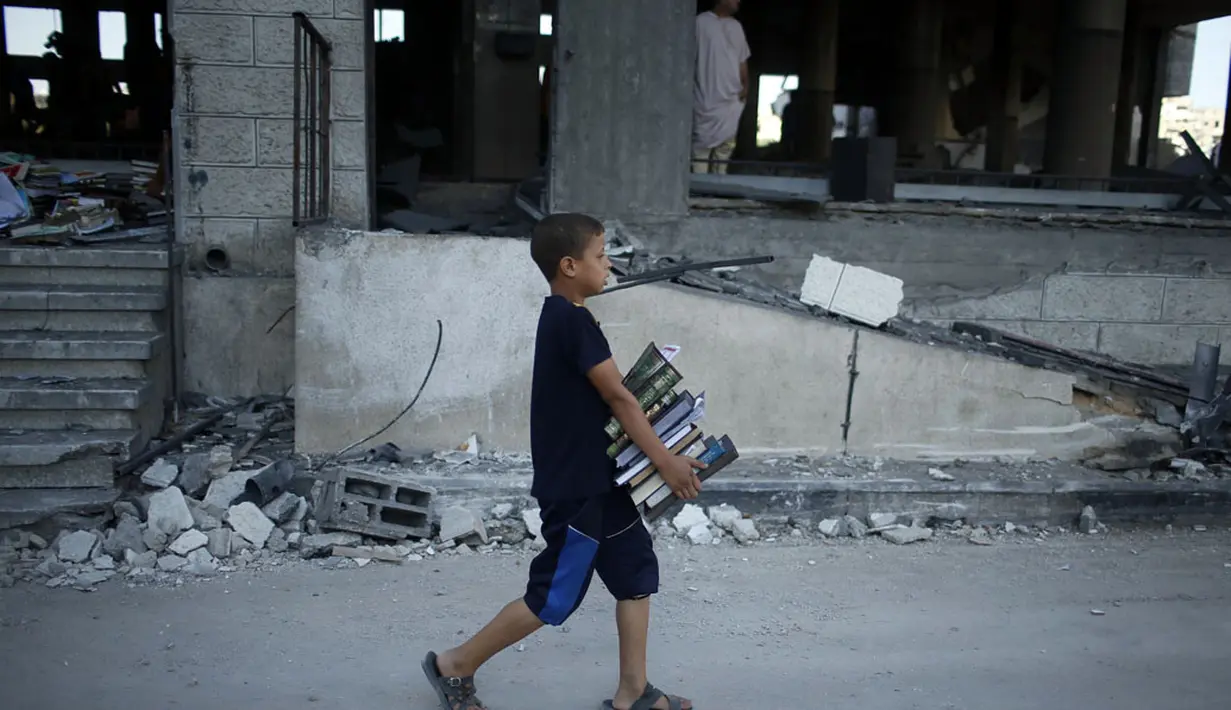 Seorang anak Palestina membawa salinan Alquran dari sebuah masjid yang rusak parah akibat serangan udara militer Israel, (9/8/2014). (REUTERS/Mohammed Salem)