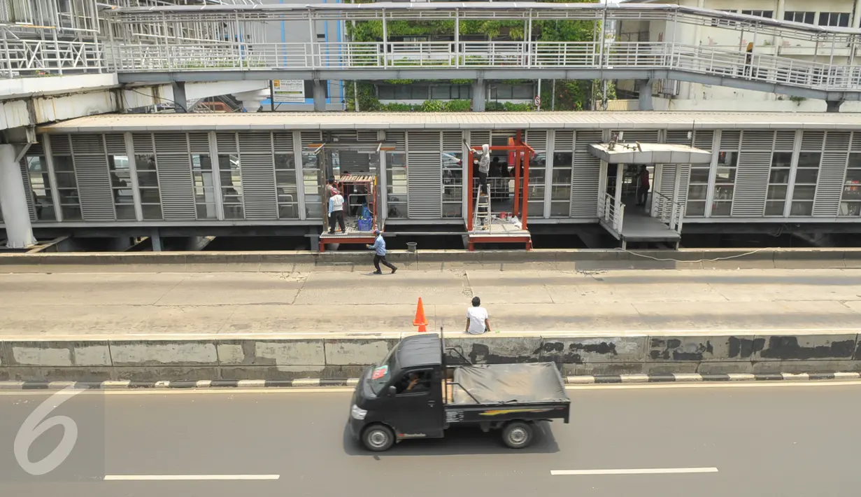 Pekerja merenovasi halte Busway Harmoni, Jakarta, Jum'at (29/1/2016). Perbaikan dilakukan pada jalur masuk penumpang karena sempat ambruk beberapa waktu lalu. (Liputan6.com/Faisal R Syam)