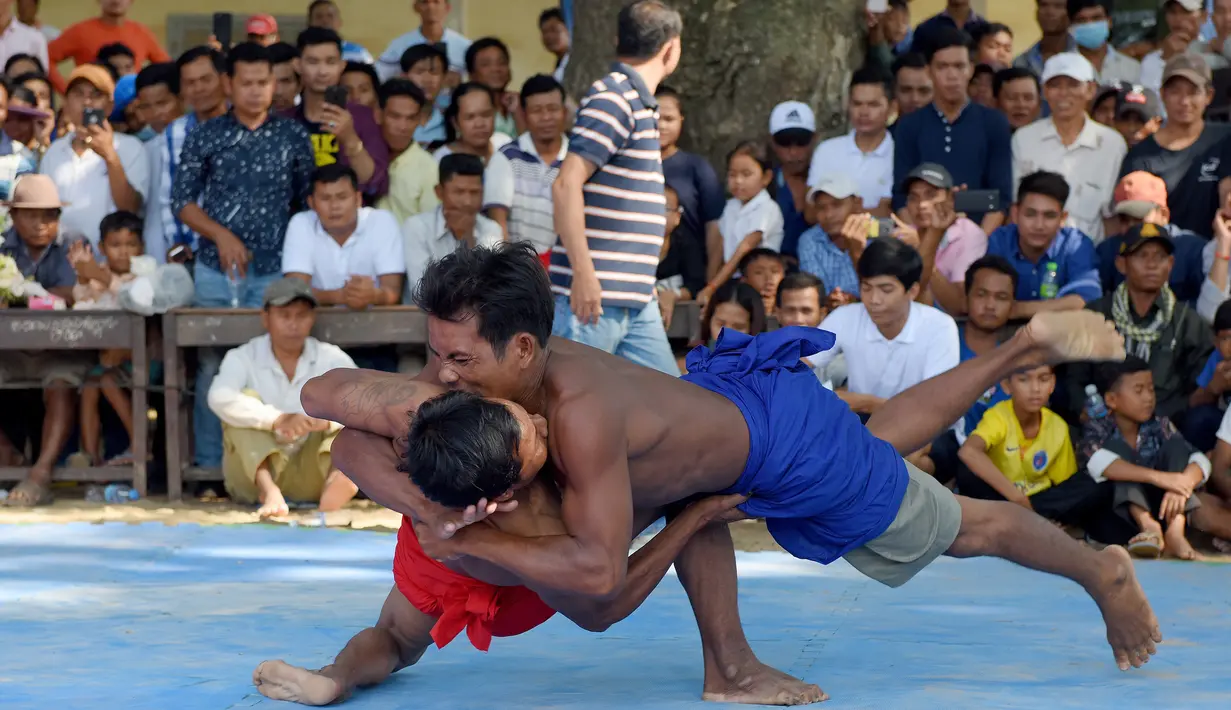 Dua pria bertarung gulat Khmer selama festival Pchum Ben atau festival kematian di desa Vihear Suor, provinsi Kandal (9/10). Warga Kamboja turun dari desa kecil di timur laut ibu kota untuk menyaksikan pertarungan ini. (AFP Photo/Tang Chhin Sothy)