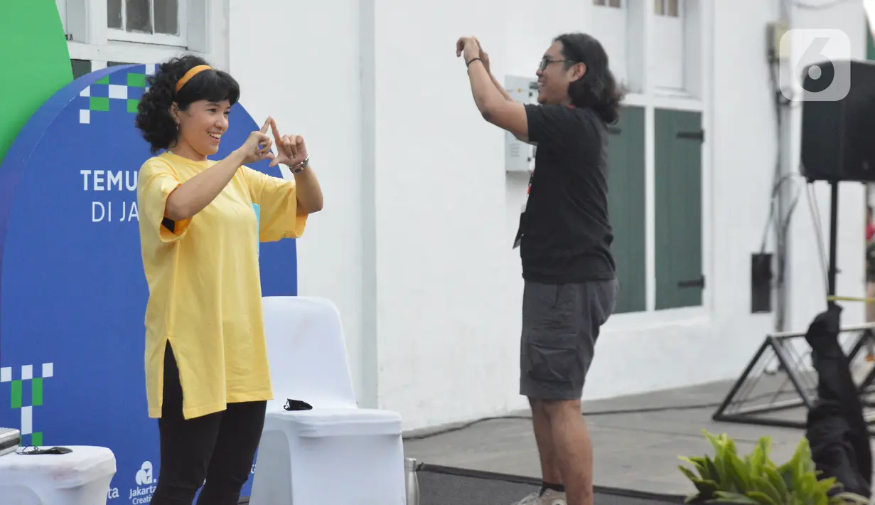 Teman tuli mengajak pengunjung untuk tampil menggunakan bahasa isyarat di Festival #IniJakarta2022, Kota Tua, Jakarta, Minggu (18/9/2022). Komunitas Tuli SilangHub mengajak pengunjung ngobrol bareng dan belajar bahasa isyarat dengan teman tuli.(Liputan6.com/Magang/Aida Nuralifa)