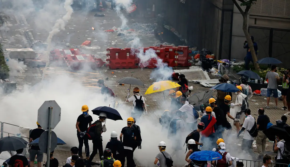 Pengunjuk rasa menghindari gas air mata yang ditembakan oleh polisi anti huru hara di luar gedung Dewan Legislatif, Hong Kong, Rabu (12/6/2019). Polisi Hong Kong telah menggunakan gas air mata ke arah ribuan demonstran yang menentang RUU ekstradisi yang sangat kontroversial. (AP Photo/Vincent Yu)