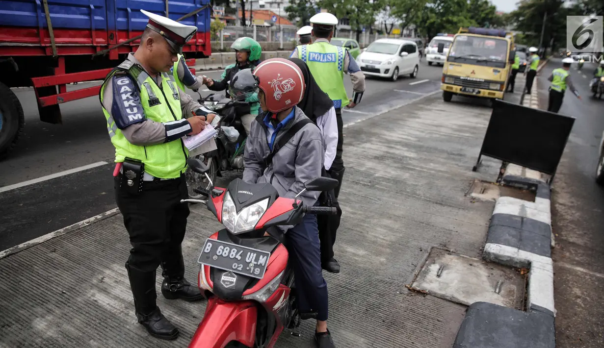 Anggota Polantas menilang pengendara motor yang melintas di jalur cepat di jalan Letjen Suprapto, Jakarta, Selasa (7/11). Sejauh ini, total ada 55.457 kendaraan yang telah ditilang oleh polisi. (Liputan6.com/Faizal Fanani)