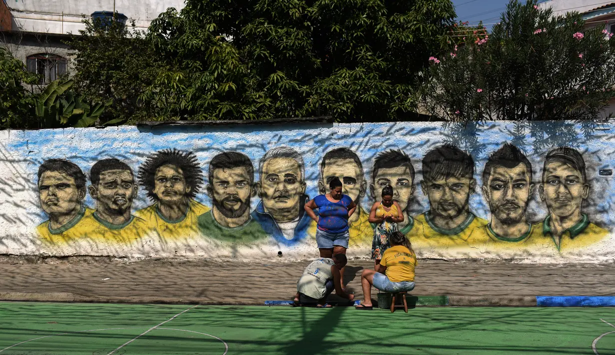 Pemandangan saat warga melukis mural Piala Dunia 2018 bergambar para pemain Brasil di dinding jalanan Camboata, Rio de Janeiro, Brasil, Kamis (31/6). (Fabio TEIXEIRA/AFP)
