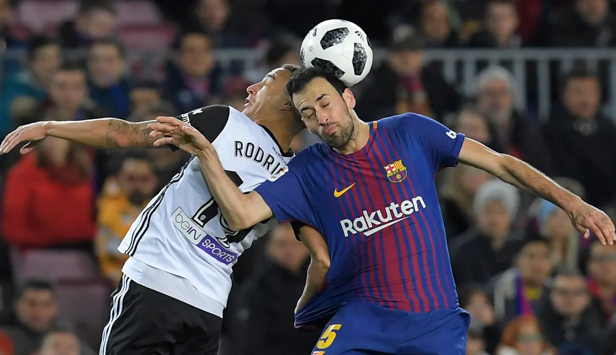 Pemain Valencia, Rodri berebut bola dengan gelandang Barcelona, Sergio Busquets pada semifinal pertama Copa del Rey di Stadion Camp Nou, Jumat (2/2). Barcelona menang 1-0 berkat gol semata wayang Luis Suarez. (AFP PHOTO/LLUIS GENE)