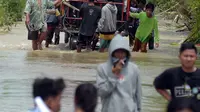 Warga melintasi banjir di Desa Sindangsari, Kabupaten Bekasi, Jawa Barat, Rabu (24/2/2021). Tim Tanggap Bencana Land Rover Club Indonesia (LRCI) melakukan drop logistik dan mengevakuasi warga yang sakit di Desa Sindangsari. (merdeka.com/Imam Buhori)