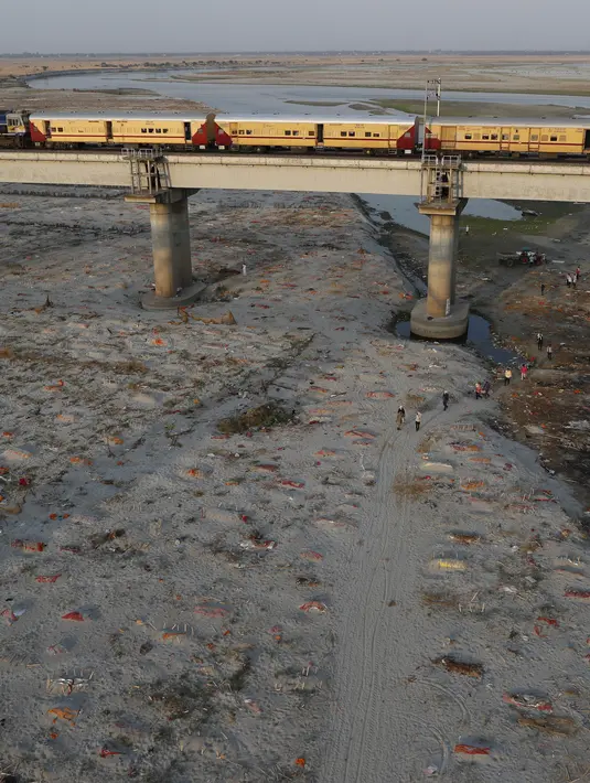 Beberapa jenazah terlihat dimakamkan di kuburan dangkal di tepi sungai Gangga di Prayagraj, 15 Mei 2021. Polisi menjangkau penduduk desa di India utara untuk menyelidiki penemuan jasad di tepi Sungai Gangga yang memicu spekulasi mereka adalah jenazah korban COVID-19. (AP Photo/Rajesh Kumar Singh)