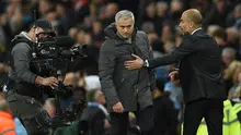 Pelatih Josep Guardiola berusaha merangkul pelatih Jose Mourinho selama pertandingan antara Manchester City melawan Manchester United di Liga Inggris di stadion Etihad, Inggris, (27/4). (AFP Photo/Oli Scarff)