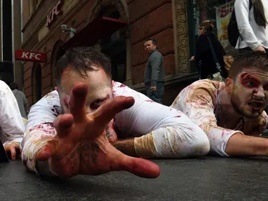 Pejalan kaki mengamati aktivis PETA yang berdandan menyerupai zombie sambil berbaring di jalan depan sebuah restoran cepat saji di Sydney, Kamis (15/6). Aksi itu sebagai bentuk protes terhadap konsumsi daging dan mempromosikan vegetarian (SAEED KHAN/AFP) 