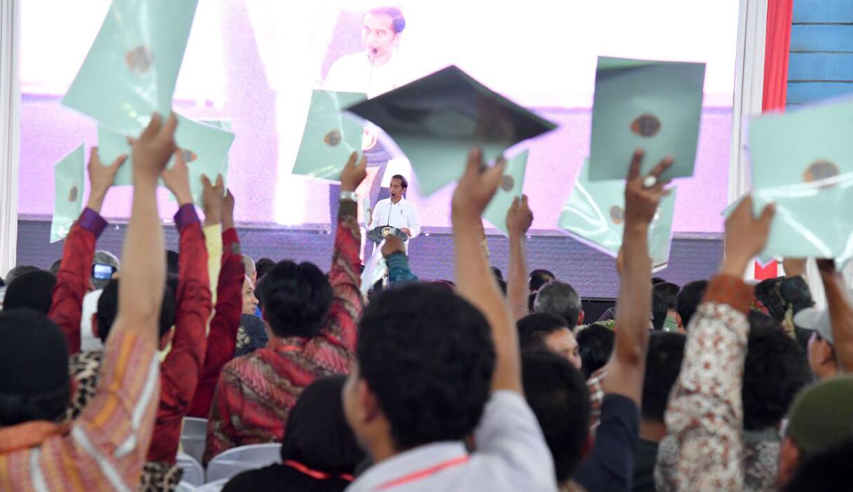 Warga Lampung mengangkat sertifikat yang dibagikan oleh Presiden Jokowi saat kunjungan kerjanya di GOR Way Handak, Kalianda, Lampung Selatan, Minggu (21/1). (Liputan6.com/Pool/Laily Rachev-Biro Pers Setpres)