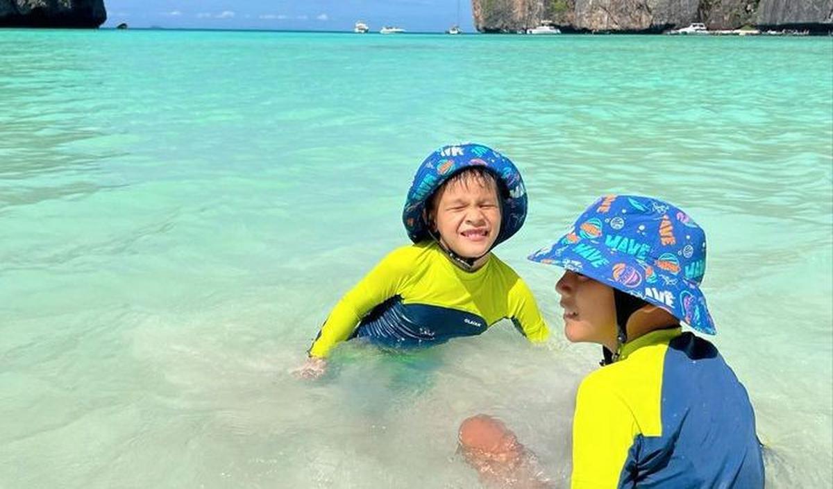 Potret Kai bersama sang kakak, Arjuna saat sedang main di pantai. Tampak pemandangan pantai yang begitu indah. Kai dan Arjuna tampak asyik berenang.<br>