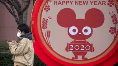 Seorang perempuan mengenakan masker berdiri dekat layar untuk perayaan Imlek Tahun Tikus Logam di Beijing, 22 Januari 2020. Otoritas kesehatan China mendesak orang-orang menghindari keramaian dan pertemuan publik di Wuhan, kota yang menjadi pusat penyebaran wabah virus corona. (AP/Mark Schiefelbein)