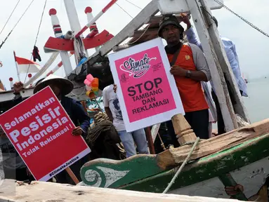 Sejumlah nelayan bersama aktivis Walhi menunjukkan poster berisi penolakan terhadap proyek reklamasi Teluk Jakarta saat upacara sedekah bumi yang lebih dikenal dengan sebutan Nadran di Muara Angke, Jakarta, Minggu (13/12/2015). (Liputan6.com/Helmi Afandi)