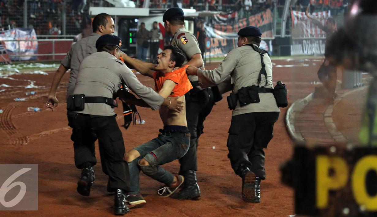 Petugas kepolisian mengamankan seorang suporter usai terlibat bentrok saat laga Persija melawan Sriwijaya FC pada lanjutan Torabika Soccer Championship presented by IM3 Ooredoo diStadion GBK Jakarta, Jumat (24/6). (Liputan6.com/Helmi Fithriansyah)
