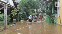 Warga berjalan melintasi banjir yang merendam kawasan Cipinang Melayu, Jakarta Timur, Jumat (19/2/2021). Banjir di kawasan tersebut akibat curah hujan yang tinggi dan meluapnya air dari Kali Sunter. (Liputan6.com/Herman Zakharia)