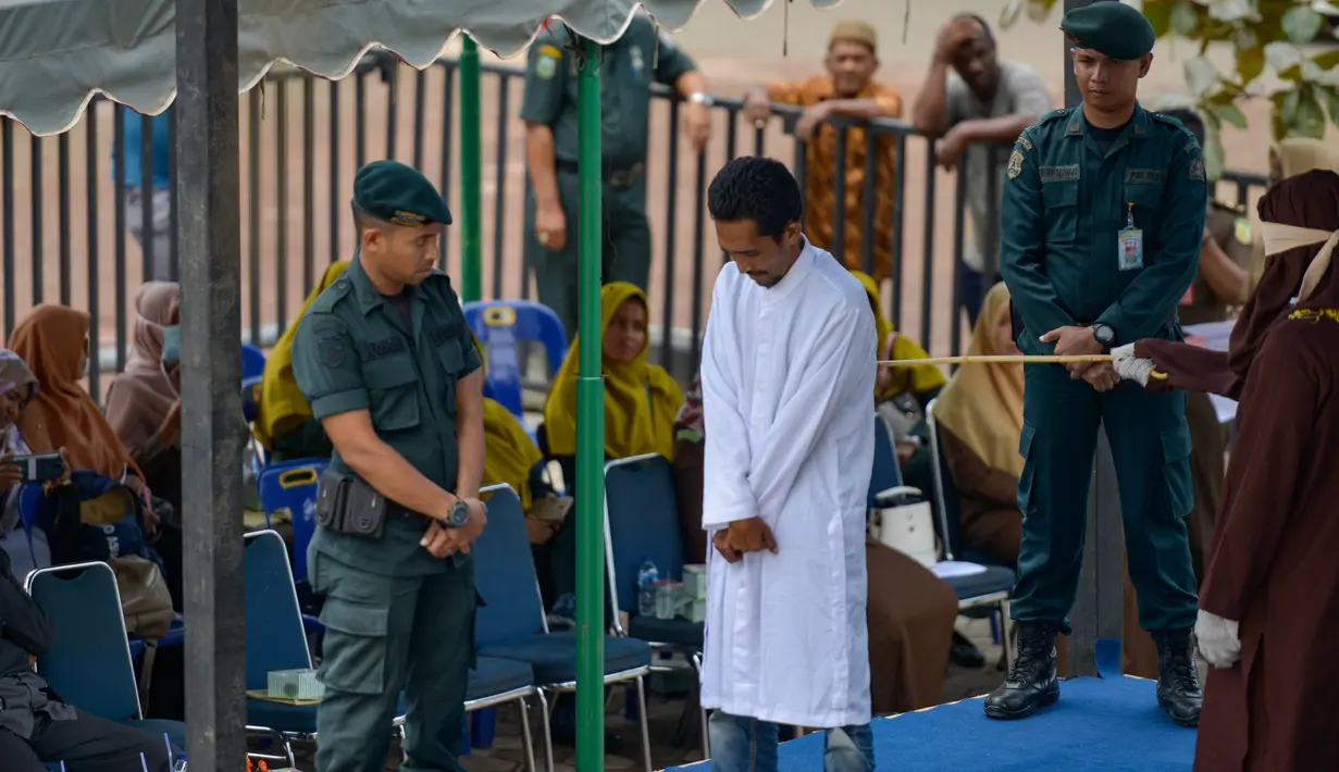Terpidana pelanggaran syariat Islam menjalani hukum cambuk di Banda Aceh, Senin (21/10/2019). Mahkamah Syariah menvonis 6 kali sabetan cambuk setelah dipotong masa tahanan dua kali cambuk terhadap empat orang pria berprofesi sopir setelah tertangkap sedang bermain judi. (CHAIDEER MAHYUDDIN / AFP)