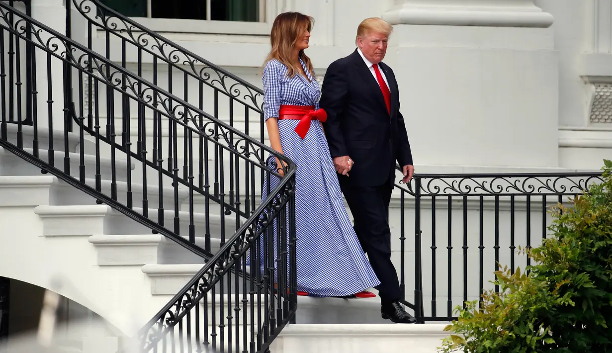 Presiden AS Donald Trump menggandeng tangan Melania Trump sambil menuruni tangga untuk menyambut keluarga militer pada acara piknik di Gedung Putih, Rabu (4/7). Pasangan yang jarang bergandengan tangan di depan umum itu tampak serasi. (AP/Alex Brandon)