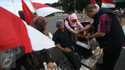 Petugas kesehatan memeriksa kondisi pengunjuk rasa yang melakukan aksi menyemen kaki di depan Istana Negara, Jakarta, Rabu (15/3). Aksi tersebut sebagai bentuk penolakan berdirinya pabrik semen di Pati. (Liputan6.com/Immanuel Antonius)