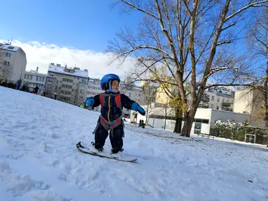 Seorang anak laki-laki berusia dua tahun bermain papan seluncur salju di taman Steinhage di Wina, Austria pada 3 Desember 2023. (Joe Klamar / AFP)