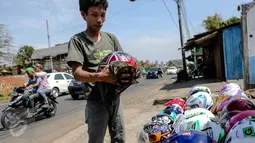 Pedagang sedang membersihkan helm dagangannya di kawasan Kali Malang, Jakarta, Selasa (14/7/2015). Meskipun mendekati hari lebaran mereka tetap berjualan aksesoris. (Liputan6.com/Faizal Fanani)
