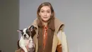 Model asal AS, Gigi Hadid menggendong anak anjing saat memamerkan rancangan Tod's di Milan Fashion Week, Milan, Italia, Jumat (23/2). (Filippo MONTEFORTE/AFP)