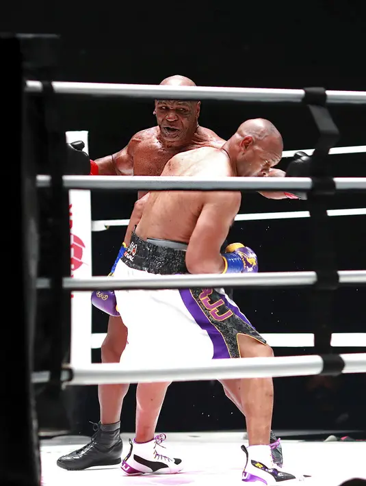 Mike Tyson melakukan pukulan terhadap Roy Jones Jr pada pertarungan tinju eksibisi di Los Angeles, Amerika Serikat, Sabtu (28/11/2020). Pertandingan berakhir tanpa pemenang alias imbang. (Joe Scarnici/Triller via AP)