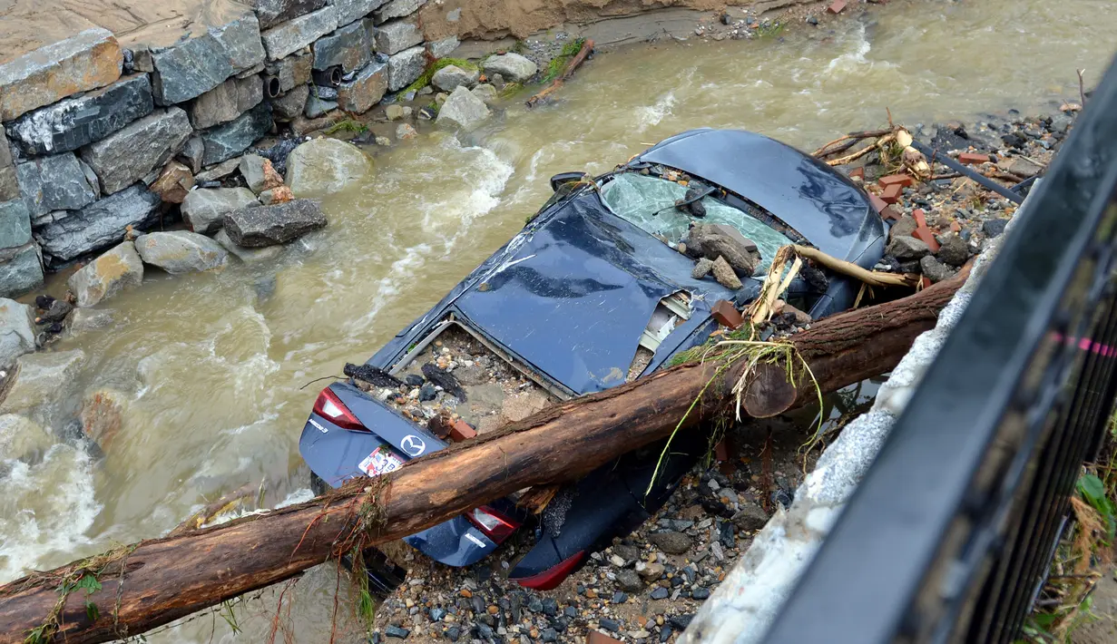 Sebuah mobil tersangkut di tepi sungai usai tersapu banjir bandang yang melanda Ellicott City, Maryland, Amerika Serikat, Senin (28/5). Belum ada laporan resmi tentang korban jiwa dan yang dirawat di rumah sakit. (AP Photo/David McFadden)