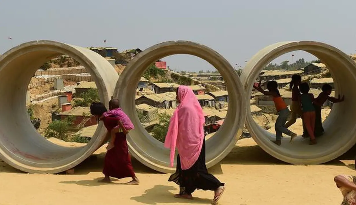 Sejumlah bocah pengungsi Rohingya bermain di pipa limbah di kamp pengungsi Kutupalong, Bangladesh (5/4). Rencananya para pengungsi Rohingya ini akan dipindahkan ke sebuah pulau terpencil di Bangladesh. (AFP Photo/Munir Uz Zaman)