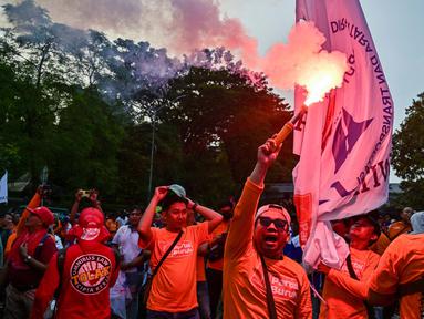 Seorang pengunjuk rasa menyalakan suar dalam aksi unjuk rasa peringatan Hari Buruh Internasional (May Day) di Surabaya, Jawa Timur, pada Kamis 1 Mei 2025. (Juni KRISWANTO/AFP)