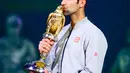 Petenis Serbia, Novak Djokovic mencium trofi Qatar Open 2017 usai menaklukkan petenis Skotlandia, Andy Murray dalam final turnamen Qatar Terbuka di Doha, Sabtu (7/1). Djokovic berhasil mempertahankan gelar Qatar Terbuka.  (AP Photo/Alexandra Panagiotidou)