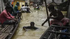 Warga menaiki perahu di atas jalan yang terendam banjir menyusul hujan lebat di Ghatal, distrik Paschim Medinipur, sekitar 100 km dari Kolkata (2/8/2021). Banjir parah akibat hujan lebat membuat jalanan di Ghatal berubah bak sungai. (AFP/Dibyangshu Sarkar)