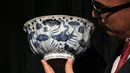  Pekerja memegang sebuah mangkuk Xuande Lobel "Fish Pond" saat ditampilkan di pelelangan Sotheby di Hong Kong (8/3). Mangkuk ini diperkirakan akan terjual dengan harga lebih dari USD 12,8 juta atau sekitar Rp 171 miliar. (AP Photo / Kin Cheung)